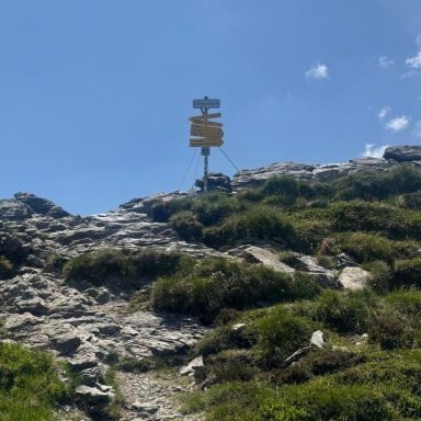 Wegweiser auf Berg bei strahlend blauem Himmel